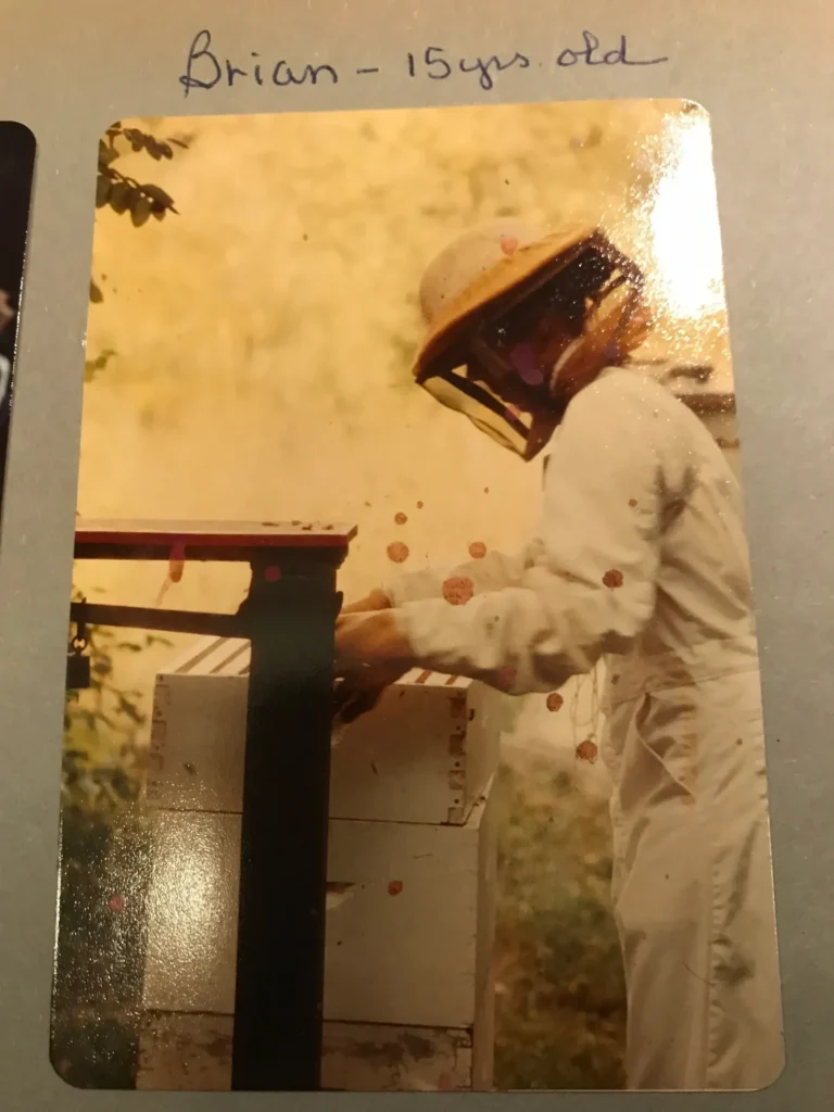 Teenager in beekeeping suit working with hive.