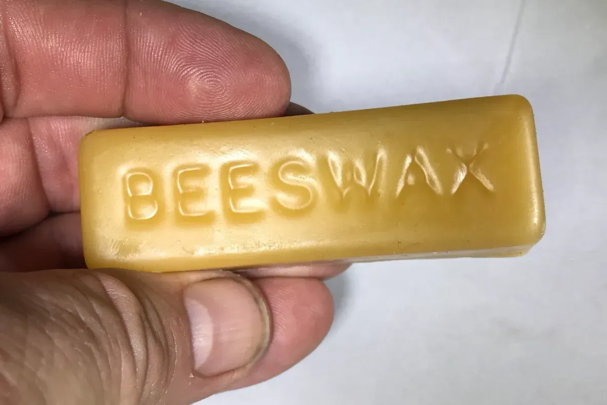 Yellow beeswax bar in hand