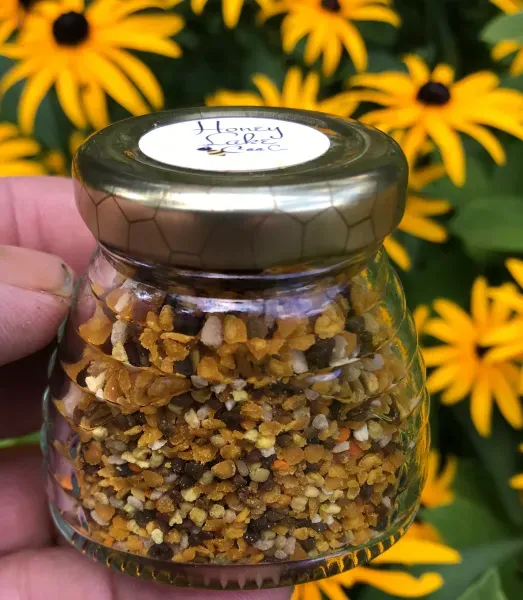 Hand holding pollen jar near flowers