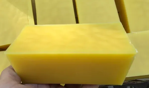 Yellow beeswax block in hand