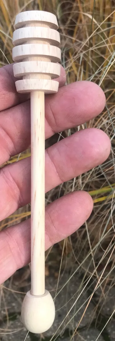 Hand holding honey dipper stick